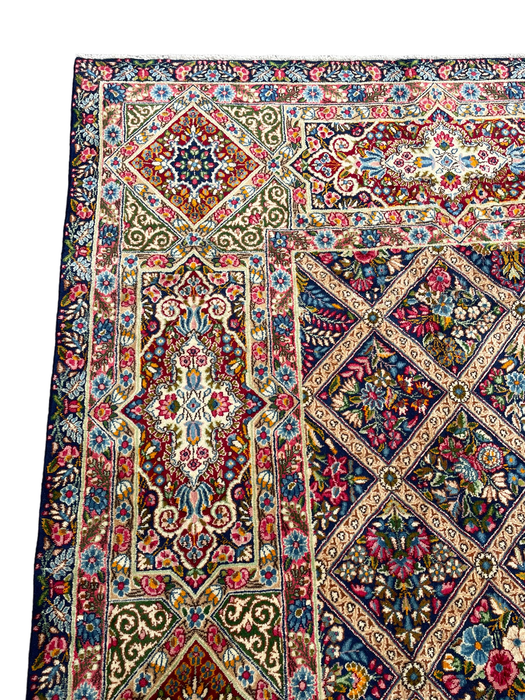 Persian Kirman indigo ground carpet, the field with repeating lozenge tiles with overall floral decoration, the main border with floral panels enclosed by the guards