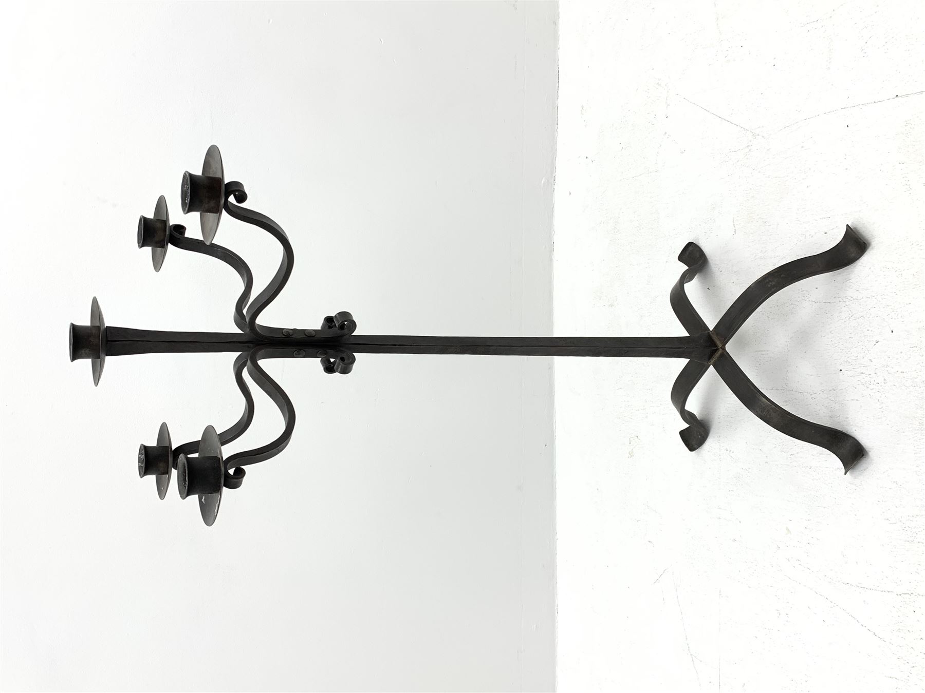 Wrought hand forged iron candle stand, four scrolled branches and central vertical branch with sconces, tapered column on four shaped and out splayed supports