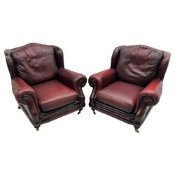 Thomas Lloyd - three-piece lounge suite, comprising of traditional shape two seat sofa (W190cm H80cm) and a pair of wingback armchairs (W100cm H91cm), each with rolled arms over turned supports with brass castors, upholstered in oxblood red leather