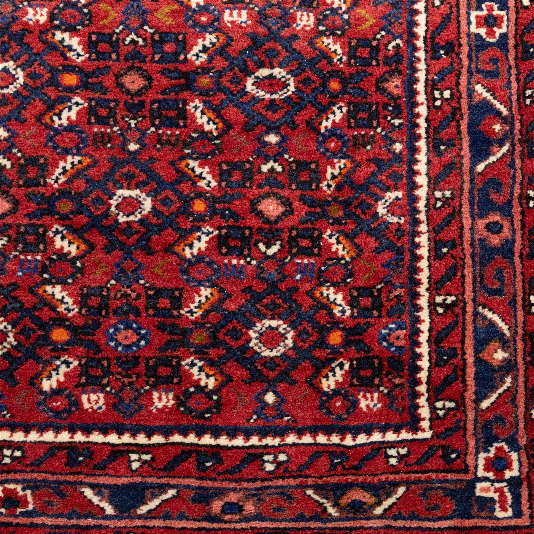 North West Persian Malayer hand-knotted runner, decorated with a dense all-over pattern of small repeating boteh and rosette motifs on a rich madder red ground, field filled with geometric floral elements arranged in a lattice design, framed by a narrow main border and flanked by slender guard borders, with cotton fringe ends 