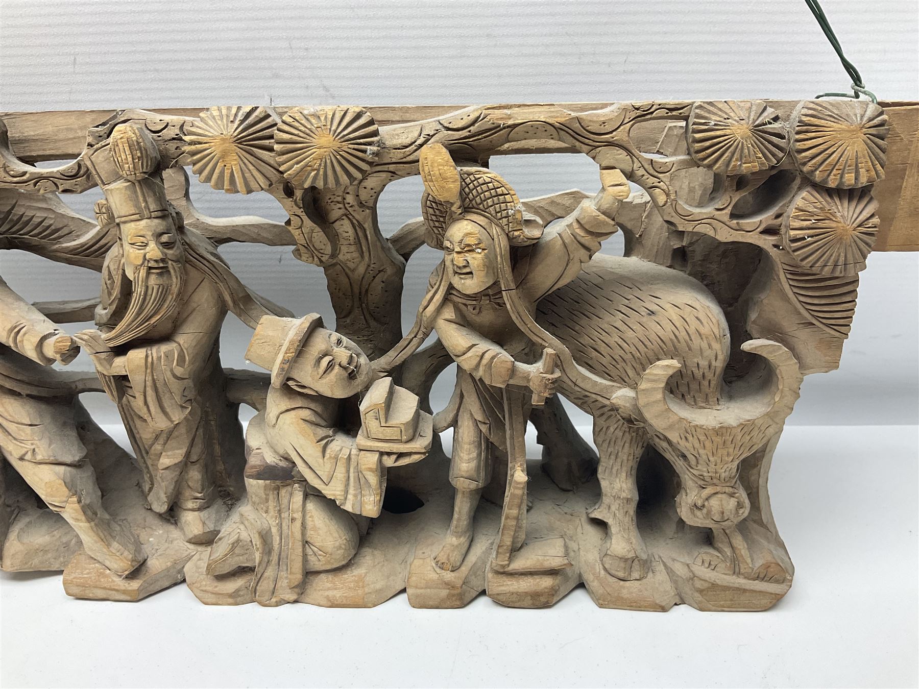 Two carved oriental wall hangings, the first example gilded depicting a temple and garden scene, the second figures in a garden, L49cm