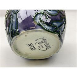 Three Minton Secessionist vases, with tube-lined stylised flower decoration, two upon a red ground and third upon a purple ground, all with printed mark to base 'Minton Ltd, No. 33', H13cm