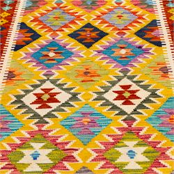 Afghan Chobi kilim flatweave runner with a repeating stepped diamond medallion design in live green, sky blue, rust, teal, purple, and ivory, framed by geometric borders in tones of orange and crimson