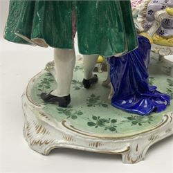 20th century Naples figure group, modelled as a seated female figure playing the lute seated, before a male figure stood holding a sheet of music, each in period dress, upon an oval base with gilt heightened scroll edge, with crowned N mark beneath, H31.5cm L33cm
