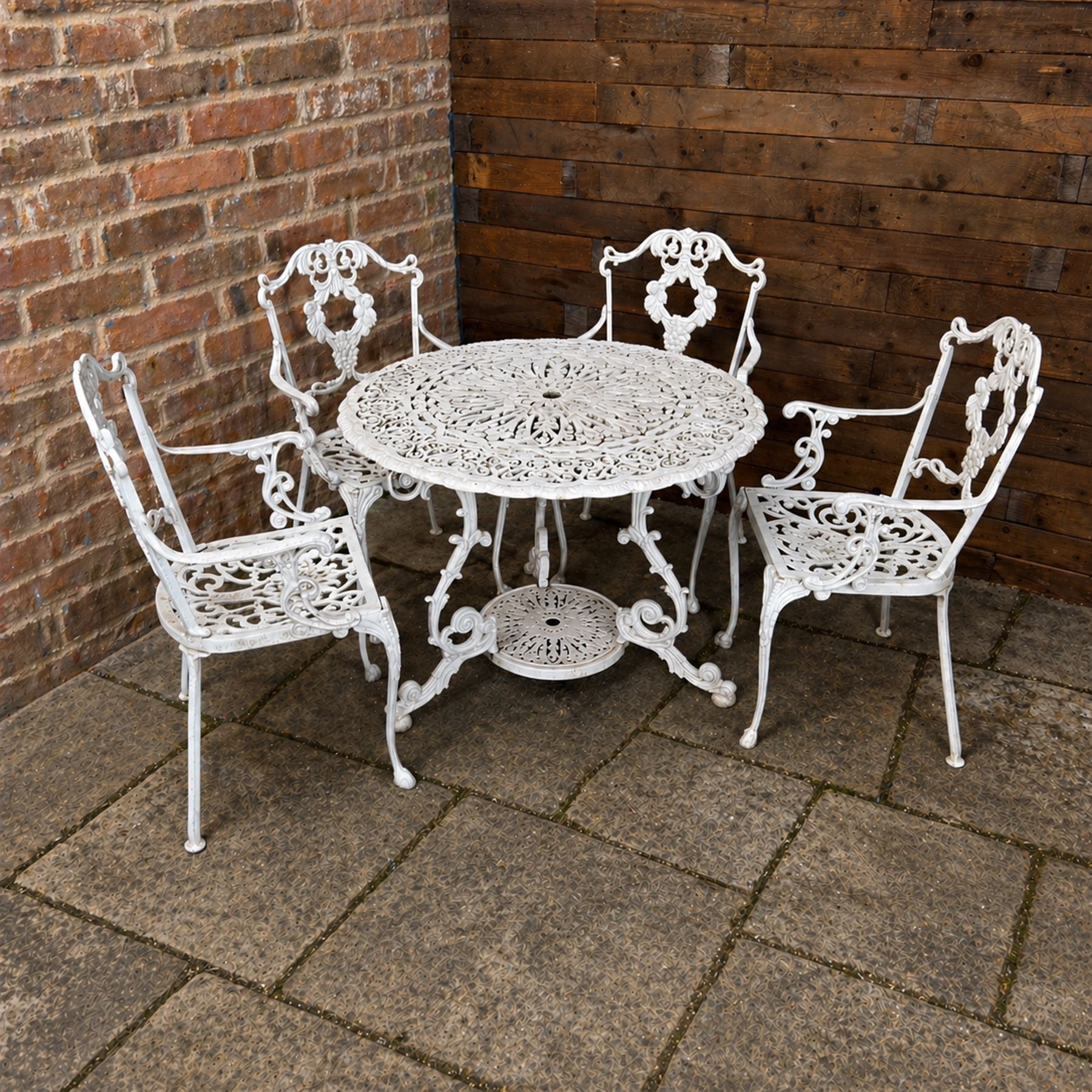Victorian design cast aluminium circular garden table and four armchairs, ornate grape design in antique white paint