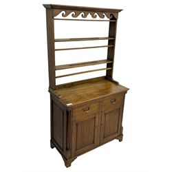 19th century and later oak dresser, moulding cornice a pierced and shaped frieze, over two open plate shelves above a base fitted with two drawers with brass swan neck handles, over panelled twin cupboard with single shelf, cantered corners on bracket feet