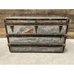Early 20th century wood and metal bound zinc travelling trunk, hinged top with three clasps, decorated with period luggage labels