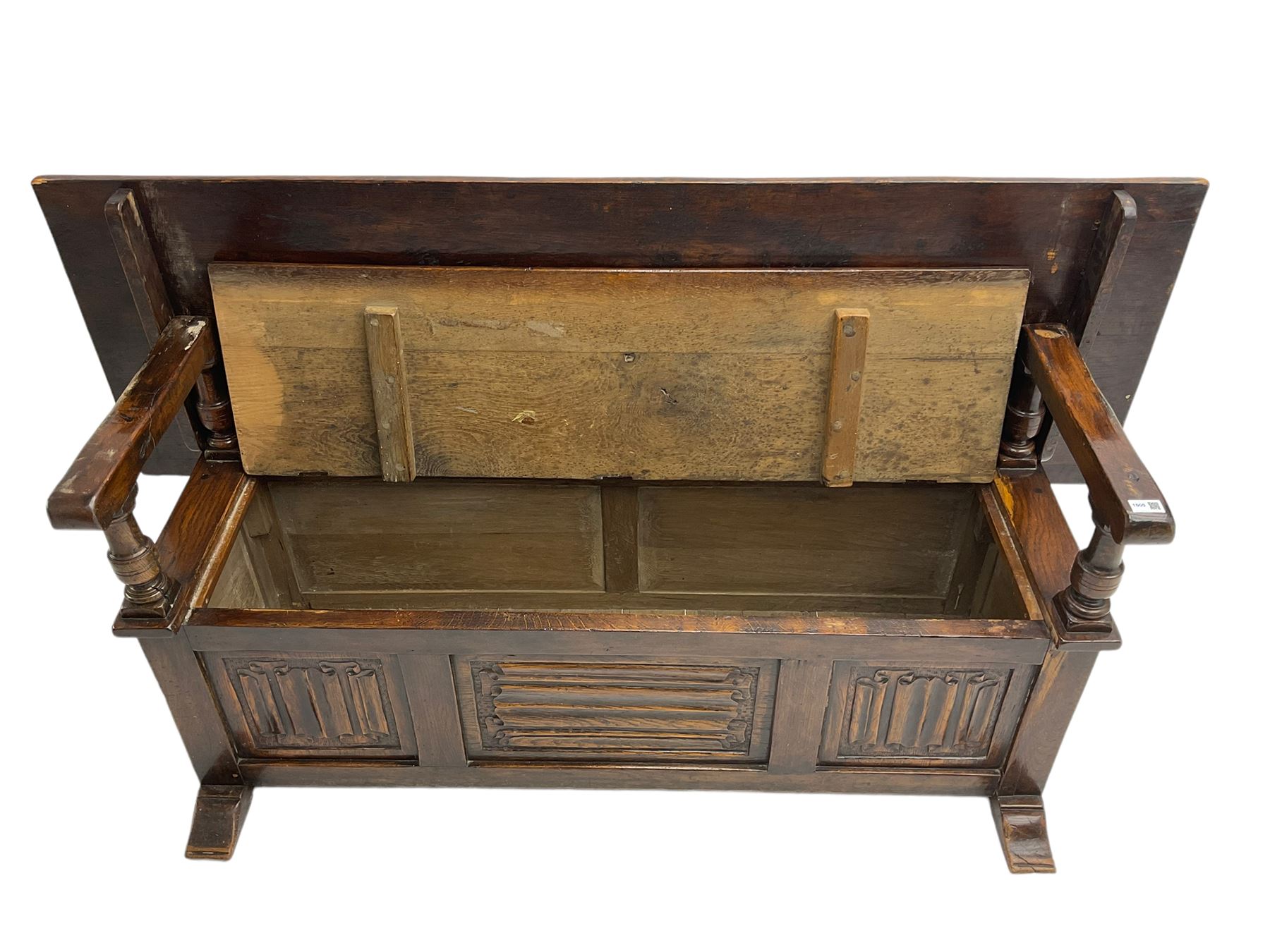 Jacobean design oak Monks bench, the front with carved linenfold panels, hinged metaphoric table back, hinged box seat compartment, on sledge feet