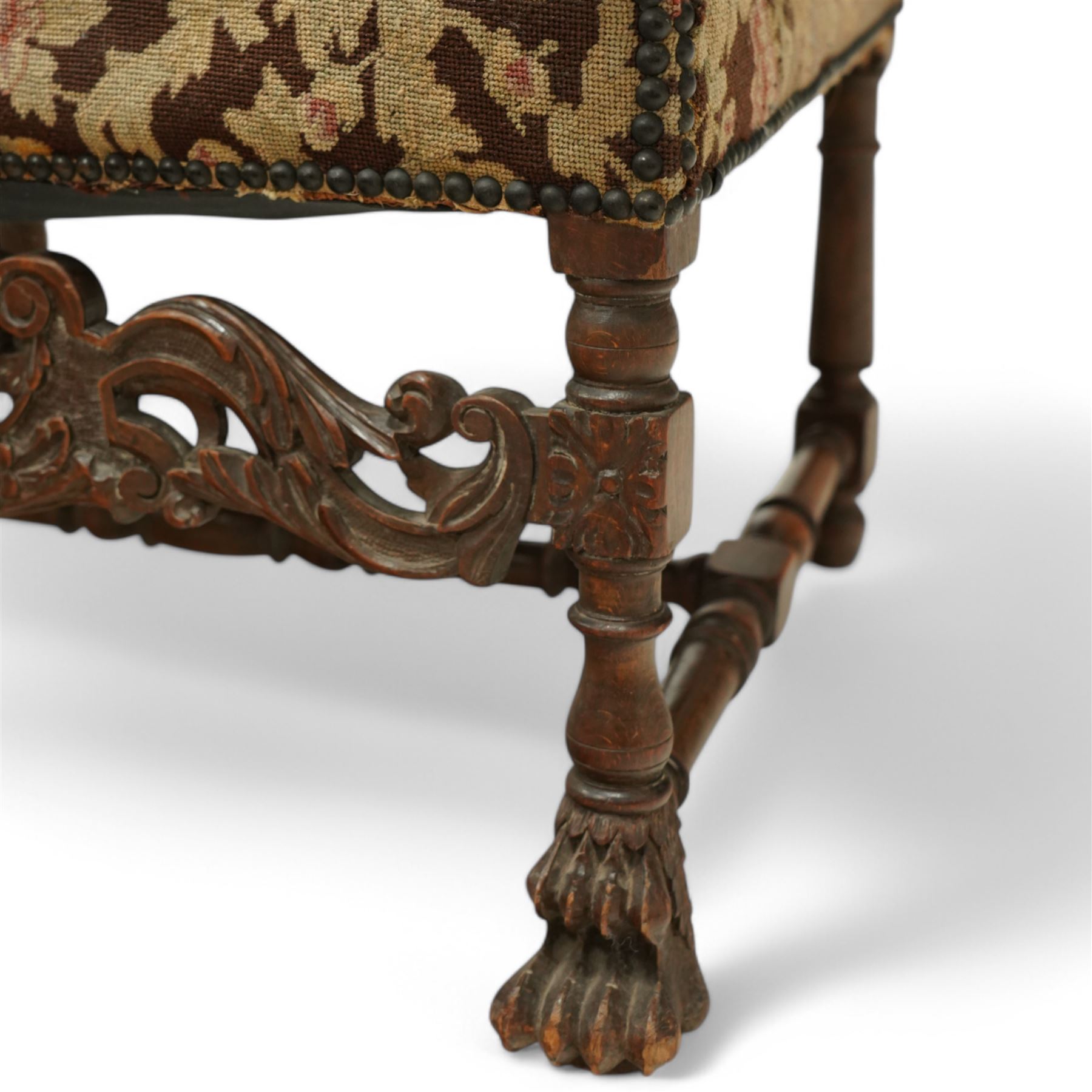 Baroque design walnut framed open armchair, arched cresting rail over acanthus carved shaped arms with scrolled terminals, upholstered in floral pattern fabric with stud bands, shaped and pierced middle rail carved with curled acanthus leaves and flower heads, on turned and block front supports terminating to paw feet, united by turned stretchers 