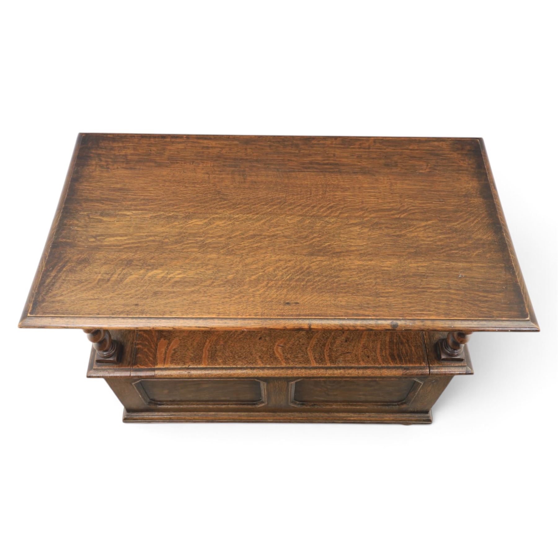 Early 20th century oak monks bench, panelled back converting to a table top, reeded armrests with barley twist uprights, hinged seat over panelled base supported on bun feet