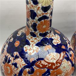 Pair of large 19th century Japanese Imari porcelain bottle vases, painted with shaped reserves of peonies, chrysanthemums and prunus blossom, each H46cm