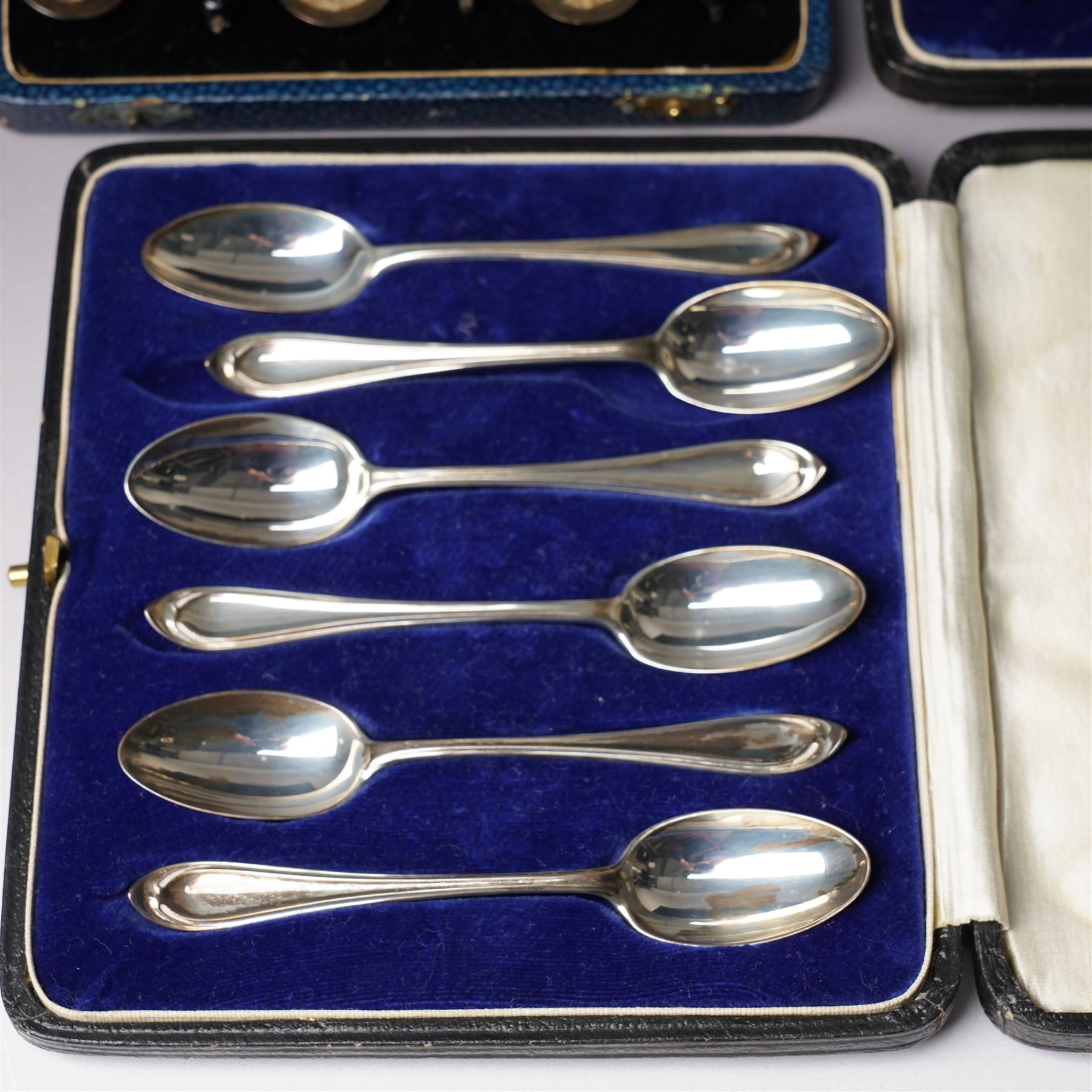 Set of six silver coffee spoons with shaped terminals, cased London 1924, another set of similar spoons London 1924 cased and a set of six silver bead knop spoons Birmingham 1936, cased