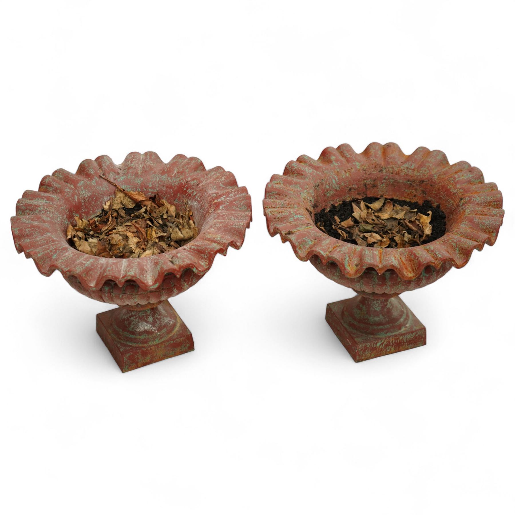 Pair of cast iron garden urns, each of flared form with crinkled edge rims and circular bodies, finished in aged red paint and raised on square bases