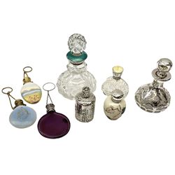 Cut glass perfume bottle of bellied form, the silver mounted cover with turquoise guilloche enamel top, hallmarked Henry Perkins & Sons, London 1927, together with a cut glass perfume bottle with silver mounted and yellow guilloche enamel lid, hallmarked Albert Carter, Birmingham 1950, Continental silver perfume bottle, of barrel form with embossed figural detail, stamped 930, scent bottle of bellied form with white metal foliate pierced overlay, amethyst glass scent bottle of flask form with foliate embossed white metal cover and suspension ring and chain, and three further examples, including one of ovoid form with painted decoration and silver cover, hallmarked for Birmingham.