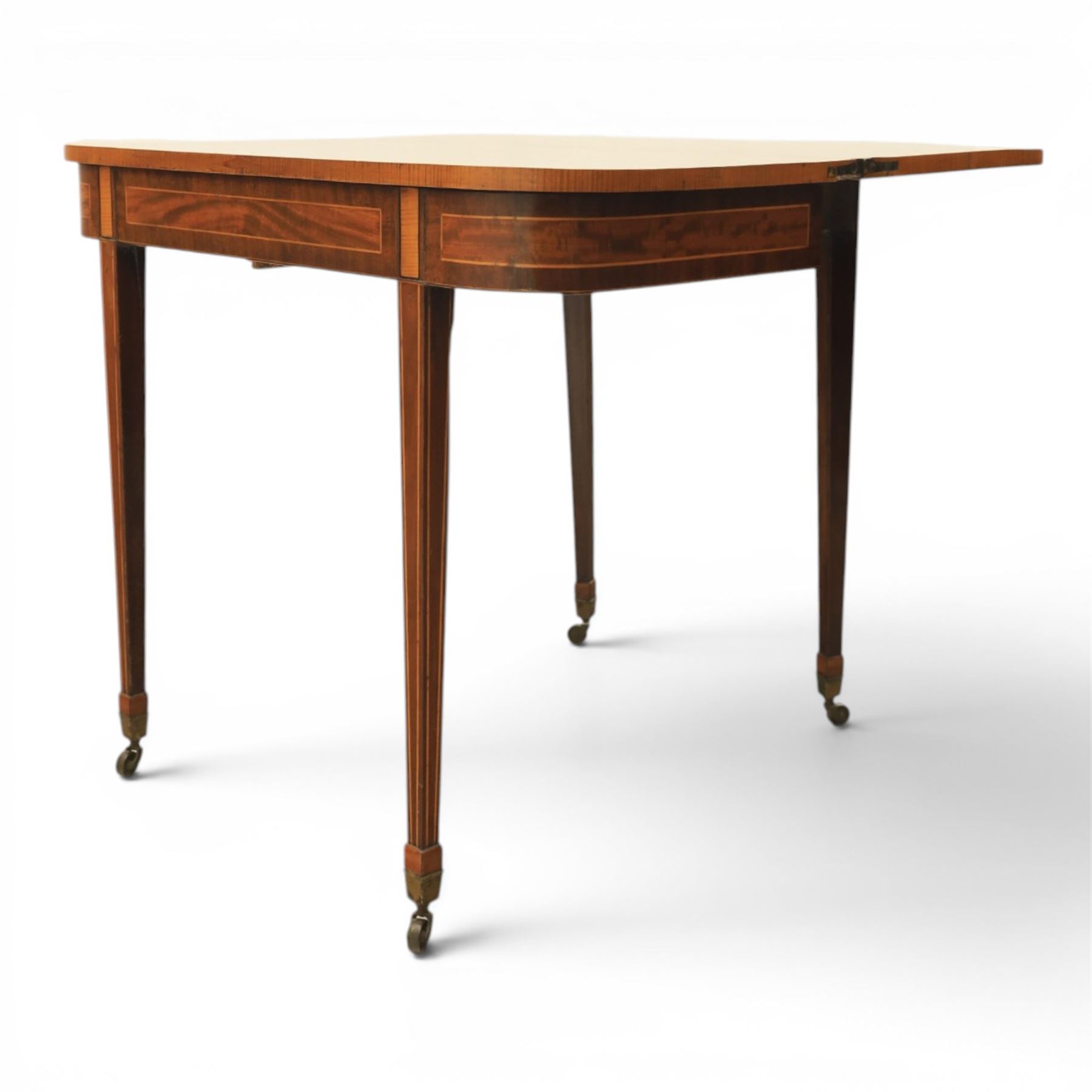 Regency mahogany fold-over tea table, rounded rectangular top with gateleg action, inlaid and crossbanded frieze, raised on squared tapering supports on brass castors