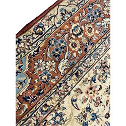 Persian ivory and peach ground rug, the ivory ground field with peach medallion and indigo spandrels, decorated with scrolled foliage and stylised floral motifs, the guarded border with signature panels decorated with flowers and birds with trailing branches