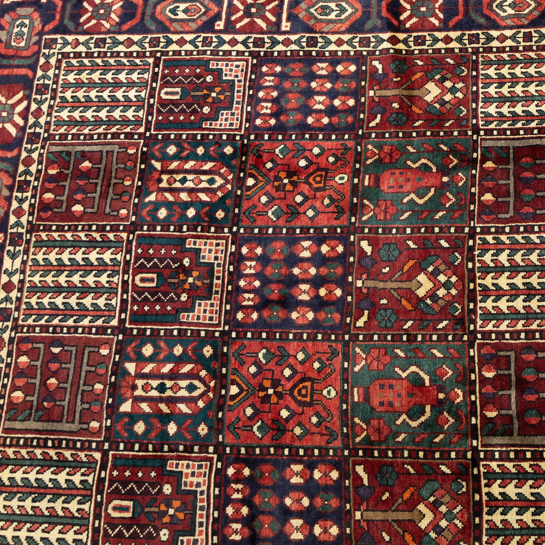 Bakhtiari wool rug, compartmented garden design field with panels of stylised trees, flowers and geometric motifs, enclosed by dark blue main border with repeating floral medallions and guard stripes