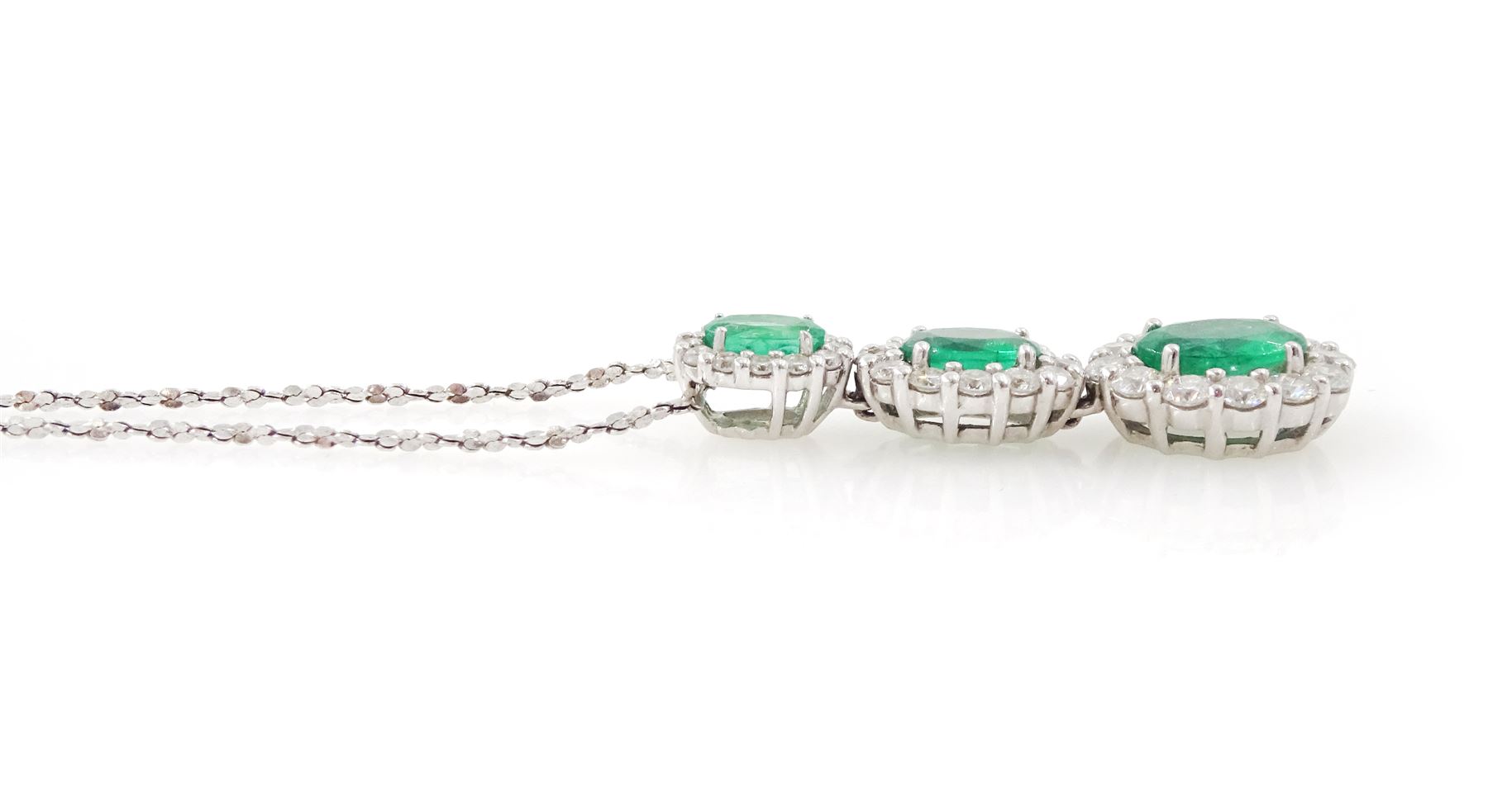 18ct white gold emerald and diamond cluster pendant, three graduating oval cut emeralds, each surrounded by round brilliant cut diamonds, Birmingham 2010, on a fine silver chain, total emerald weight approx 1.05 carat, total diamond weight approx 0.55 carat