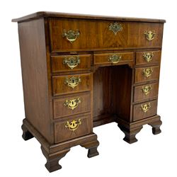 Early 18th century Queen Anne figured walnut kneehole desk with secretaire drawer, moulded and book matched top with walnut band, the top drawer with fall front enclosing small drawers and pigeon holes, fitted with nine drawers and central recessed cupboard, on ogee bracket feet