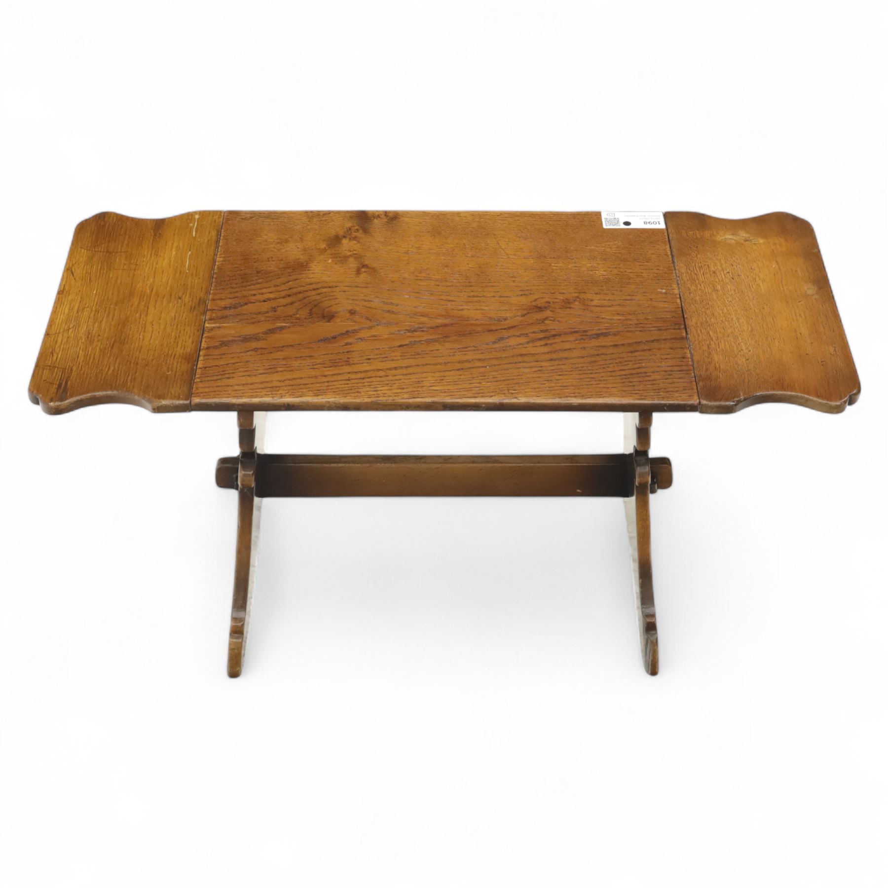 Early 20th century oak drop leaf cottage table, rectangular top with twin hinged leaves, on shaped trestle end supports united by central stretcher