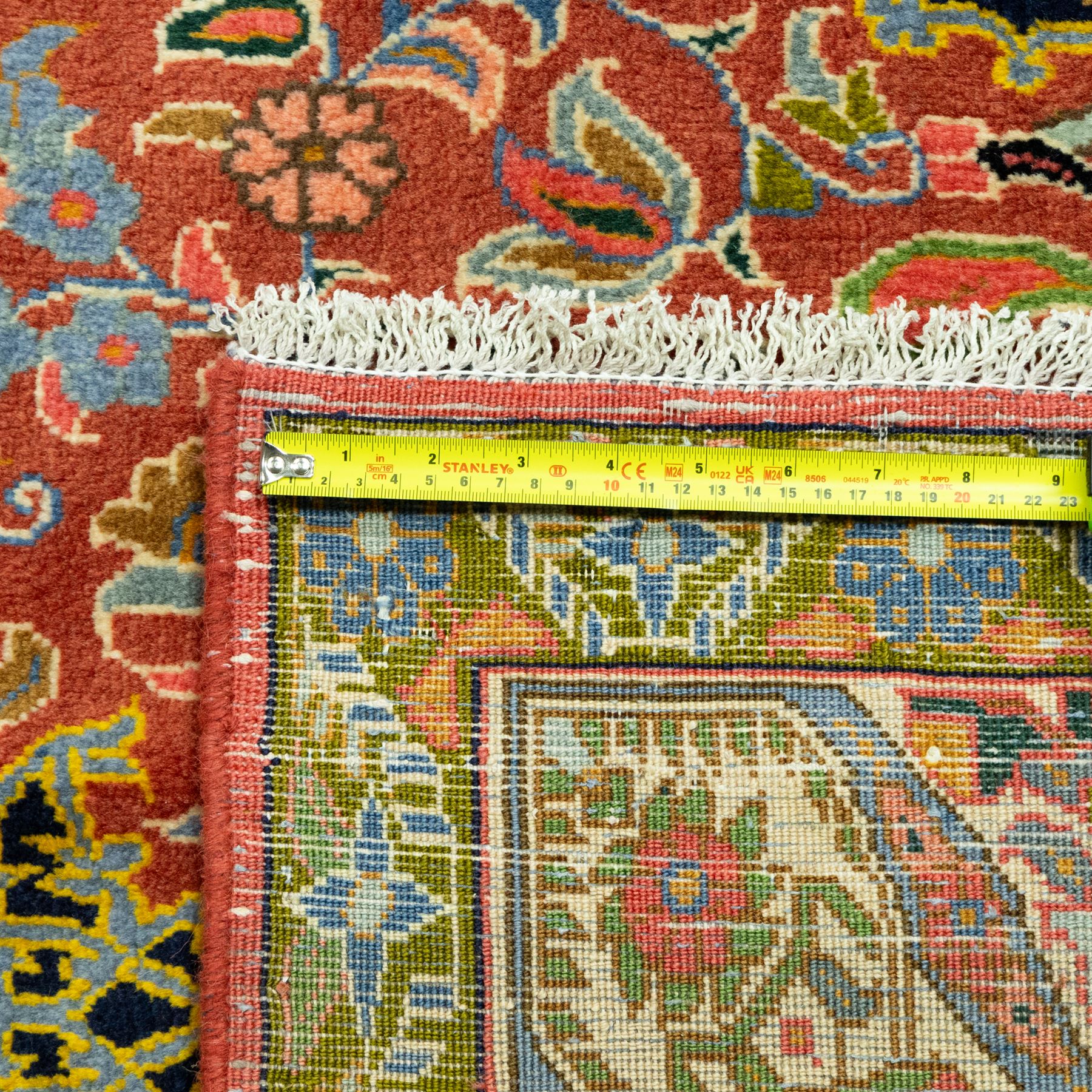 South Persian Sirjan hand-knotted carpet, terracotta ground, with a central shaped dark navy floral medallion with pendants, surrounded by scrolling foliate and floral motifs incorporating palmettes, rosettes and stylised vine work in blue, green and ivory tones, enclosed by dark navy spandrels and a wide green and ivory border with repeating palmettes and angular leaf motifs, flanked by patterned guard stripes, with cotton fringes