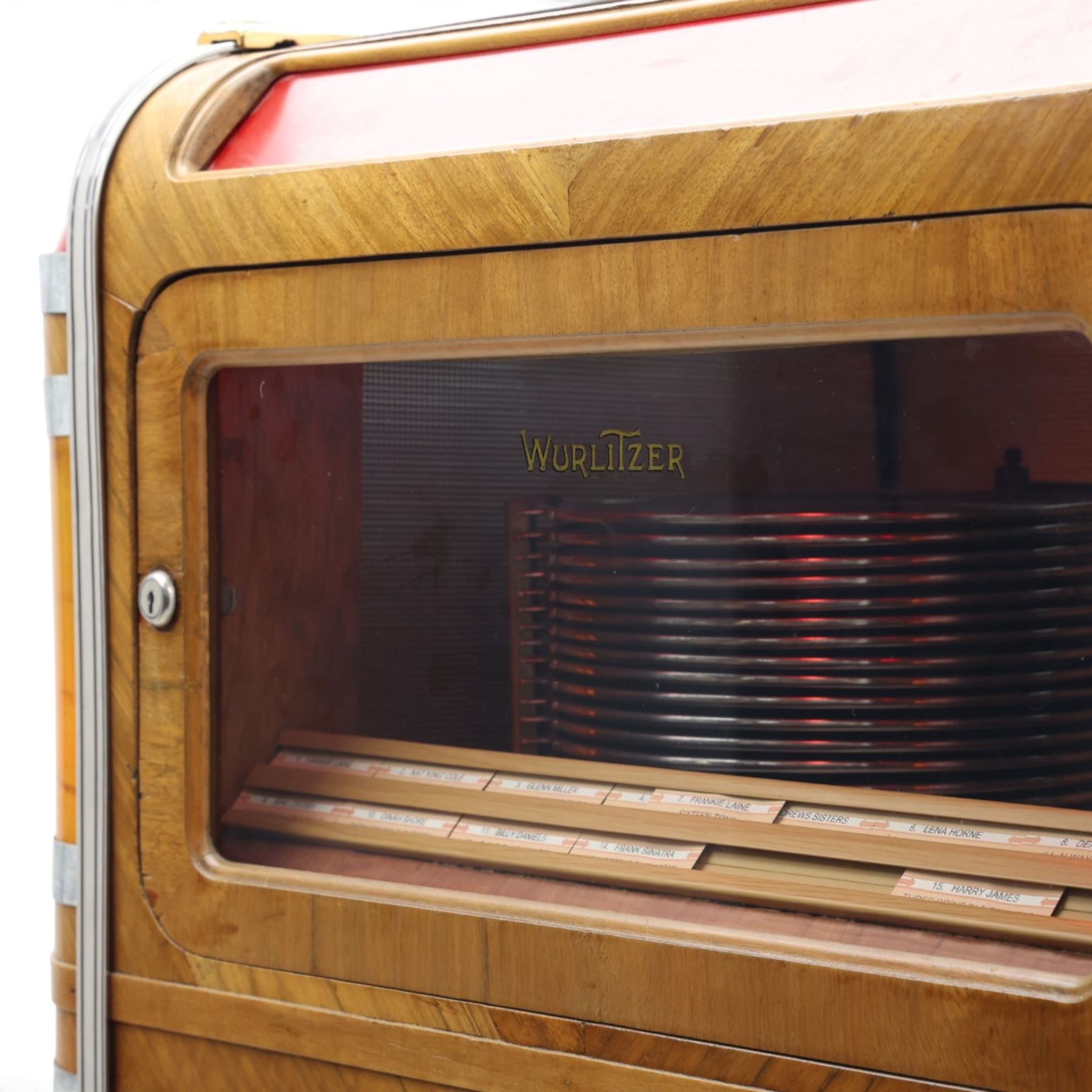 Rudolf Wurlitzer Company - Model 616 'Simplex' 1937 jukebox, figured walnut veneered cabinet with illuminated red and amber side panels enclosed by chromed uprights, glazed upper record compartment, cast Art Deco speaker grille, coin-operated push-button selection panel with circular title index, raised on a moulded base