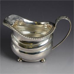 George III silver milk jug, of oval form with oblique gadrooned rim and acanthus leaf capped handle, upon four bun feet, hallmarked London 1819, maker's mark worn and indistinct, H10cm