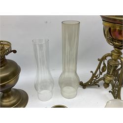 Oil lamp with ceramic reservoir printed with a hunting scene, large brass oil lamp raised on three legs with floral detail and three other oil lamps, tallest example H45cm, in two boxes 