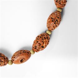 Chinese Hediao necklace, comprising twenty-one pierced and carved seeds strung with smaller beads, the carvings depicting birds among foliage, crabs and fish, figures and warriors, and other traditional scenes, length 82cm 