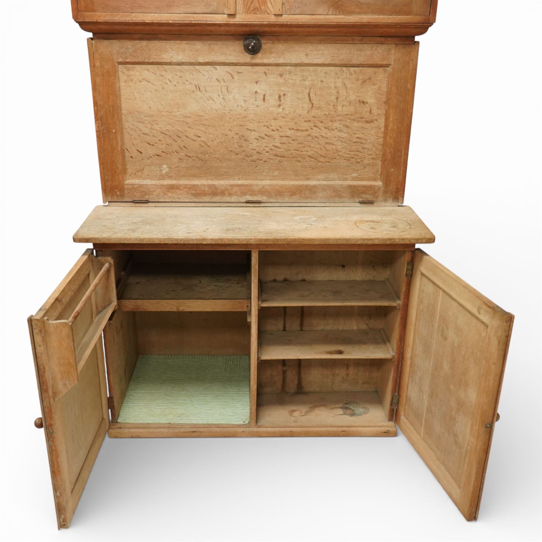 Early 20th century 'Quicksey' oak kitchen larder, rectangular moulded cornice over a pair of panelled cupboard doors, the fall front enclosing a white enamel work surface with fitted interior comprising original glass drawers, storage compartments and shelf, the lower section with twin panelled cupboard doors enclosing shelving and divided storage, raised on a plinth base