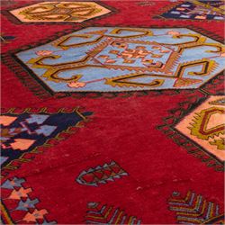 Turkish Anatolian hand-knotted carpet, red field centred by a large pale blue geometric medallion flanked by pink octagonal medallions, scattered stylised motifs, enclosed by multiple geometric borders