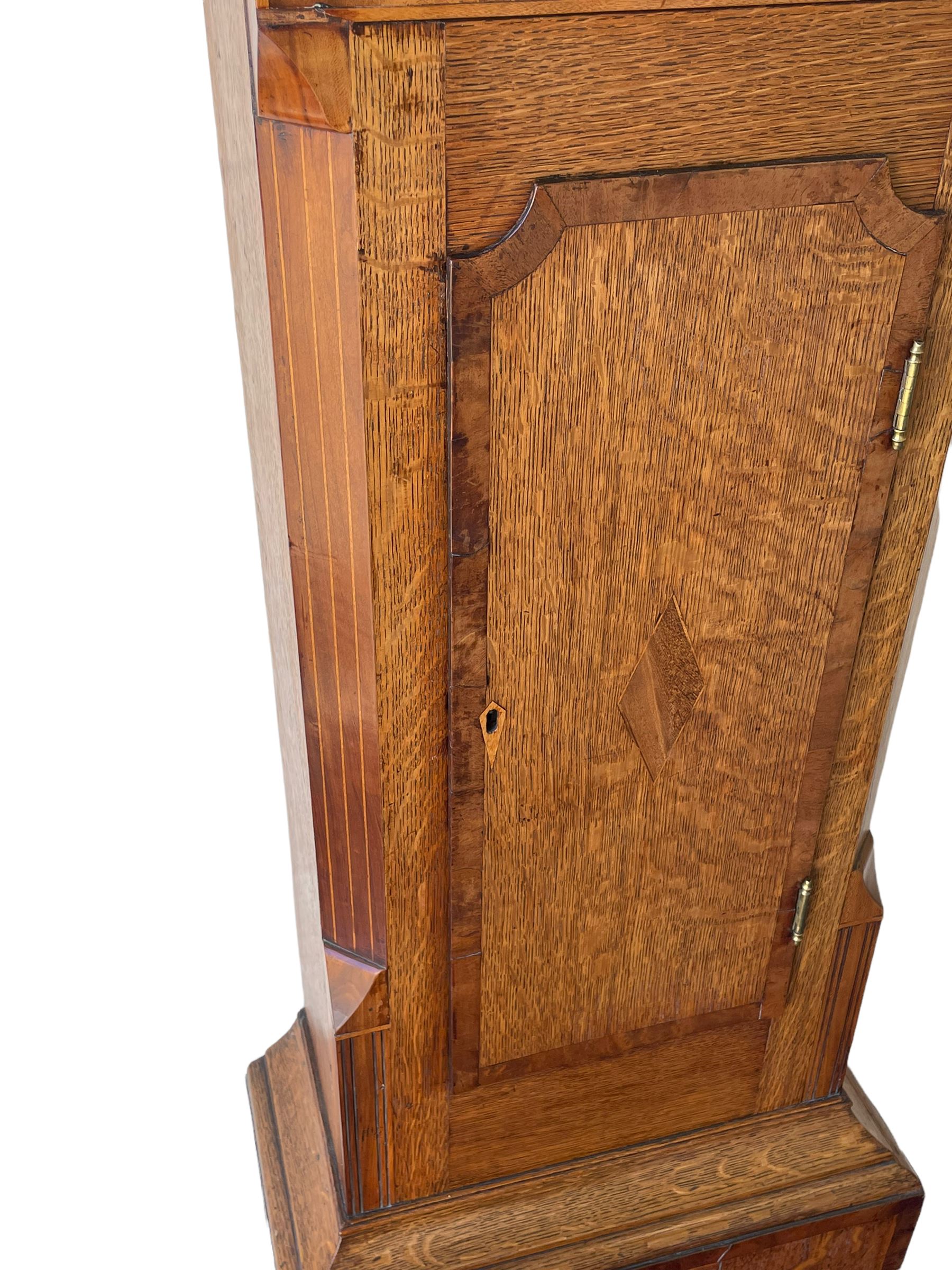 An oak and mahogany longcase clock by William Hewson, Lincoln c 1860, with a swans neck pediment, ball and spire finials and brass paterae, break arch hood door flanked by reeded pilasters with brass capitals, oak trunk with canted corners and a short oak door with mahogany crossbanding, conforming plinth with applied skirting, fully painted dial with Roman numerals, minute track and subsidiary seconds dial, matching brass stamped hands and winding collets, depiction of a  sportsman to the break arch and corresponding game birds to the spandrels, dial pinned directly to an eight-day rack striking movement with a recoil anchor escapement, striking the hours on a bell. Original casemakers label pasted to the inside of the case 