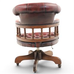 Captains swivel desk chair upholstered in oxblood leather, buttoned back and seat, shaped arm bow raised on turned spindles, five spoke base raised on castors