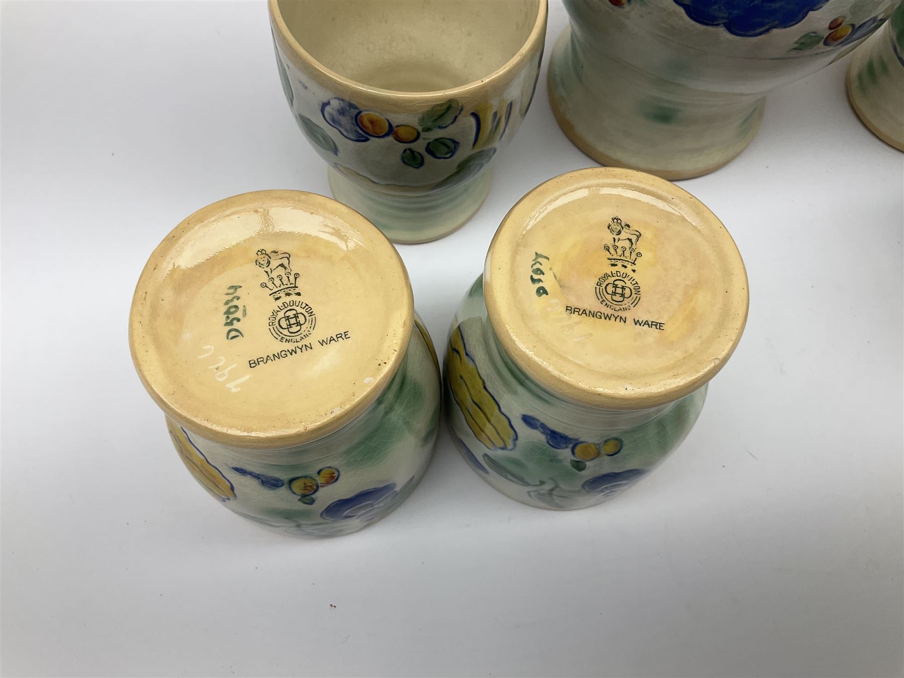 Early 20th century Royal Doulton Brangwyn Ware jug and set of six beakers, designed by Frank Brangwyn RA, all decorated in the Harvest pattern with stylised leaves and fruit on mottled peach and green ground, all with printed marks beneath, date code for 1920s, largest H18cm
