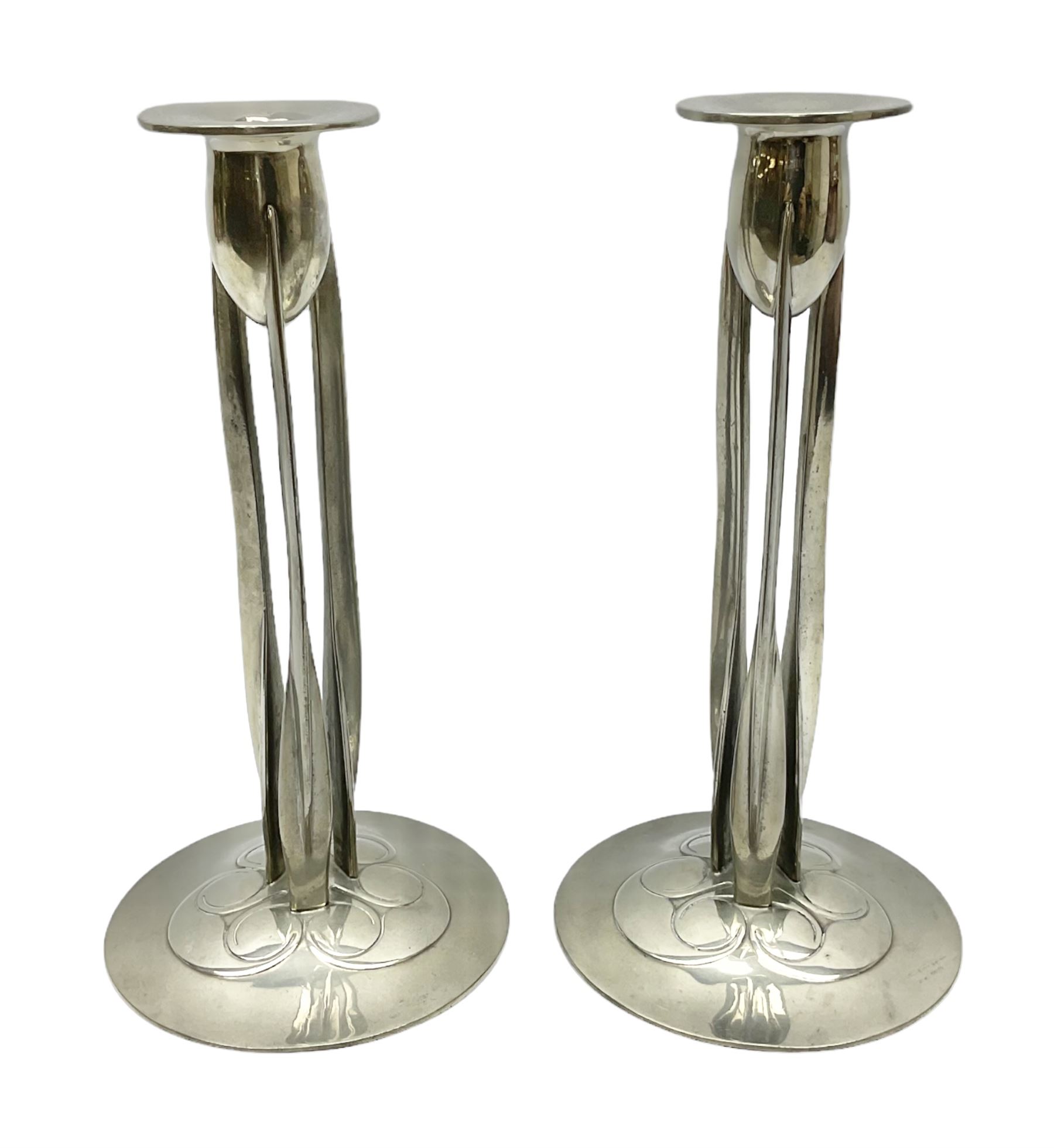 Archibald Knox (1864-1933) for Liberty & Co, pair of Tudric pewter candlesticks, the bud shaped sockets raised upon three angular fin supports and a slightly domed circular base with cast stylised foliate decoration, each stamped beneath Tudric 0223, H30cm