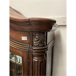 Kevin Charles American walnut display cabinet, illuminated interior, shell carved pediment above four bevel edge doors enclosing six glazed shelves above one central long drawer flanked by two short drawers, above three cupboards, carved bracket supports 