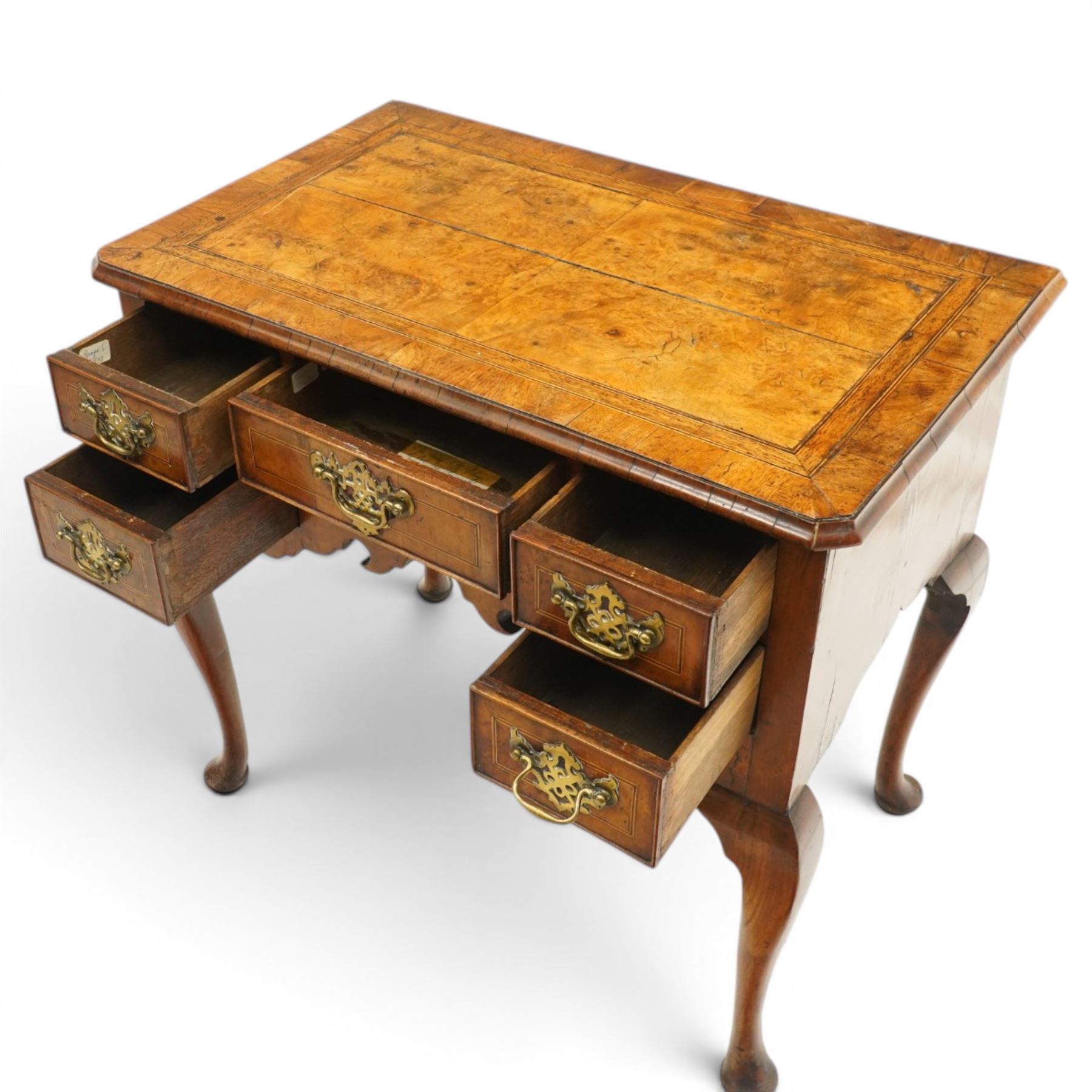 18th century figured and burr walnut lowboy, the rectangular canted top with book-matched veneer and crossbanding with moulded edge, fitted with an assortment of five cock-beaded drawers with original pierced brass handle plates, over a shaped apron, raised on cabriole supports with pad feet