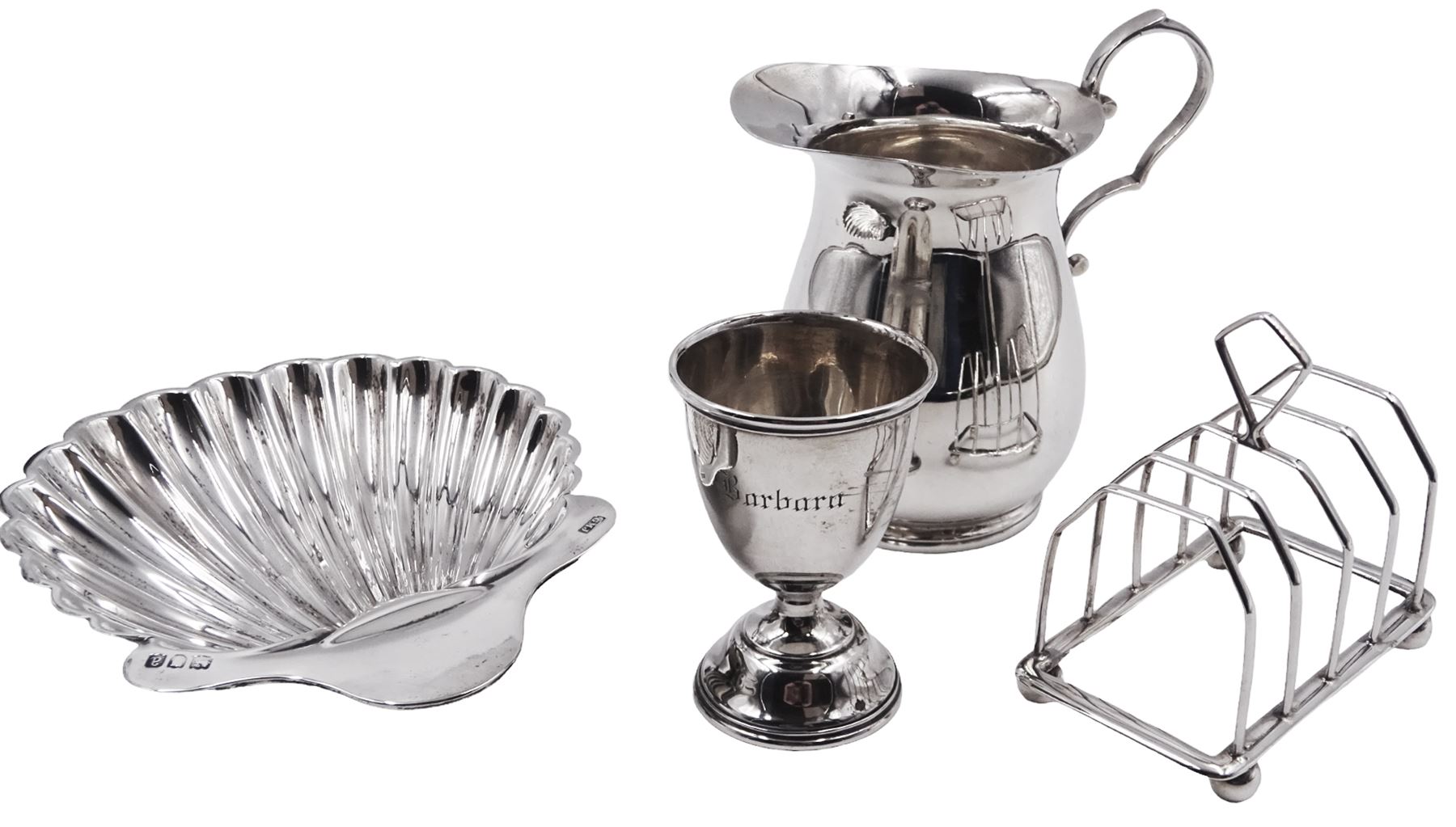 Victorian silver shell butter dish, upon three ball feet, hallmarked Josiah Williams & Co, London 1896, together with a 1920s silver egg cup, engraved 'Barbara', hallmarked Joseph Gloster Ltd, Birmingham 1929, a 1920s silver five bar toast rack, with loop handle, hallmarked William Greenwood & Sons, Birmingham 1928 and a mid 20th century silver milk jug, hallmarked James Dixon & Sons Ltd, Sheffield 1944, tallest H8.5cm
