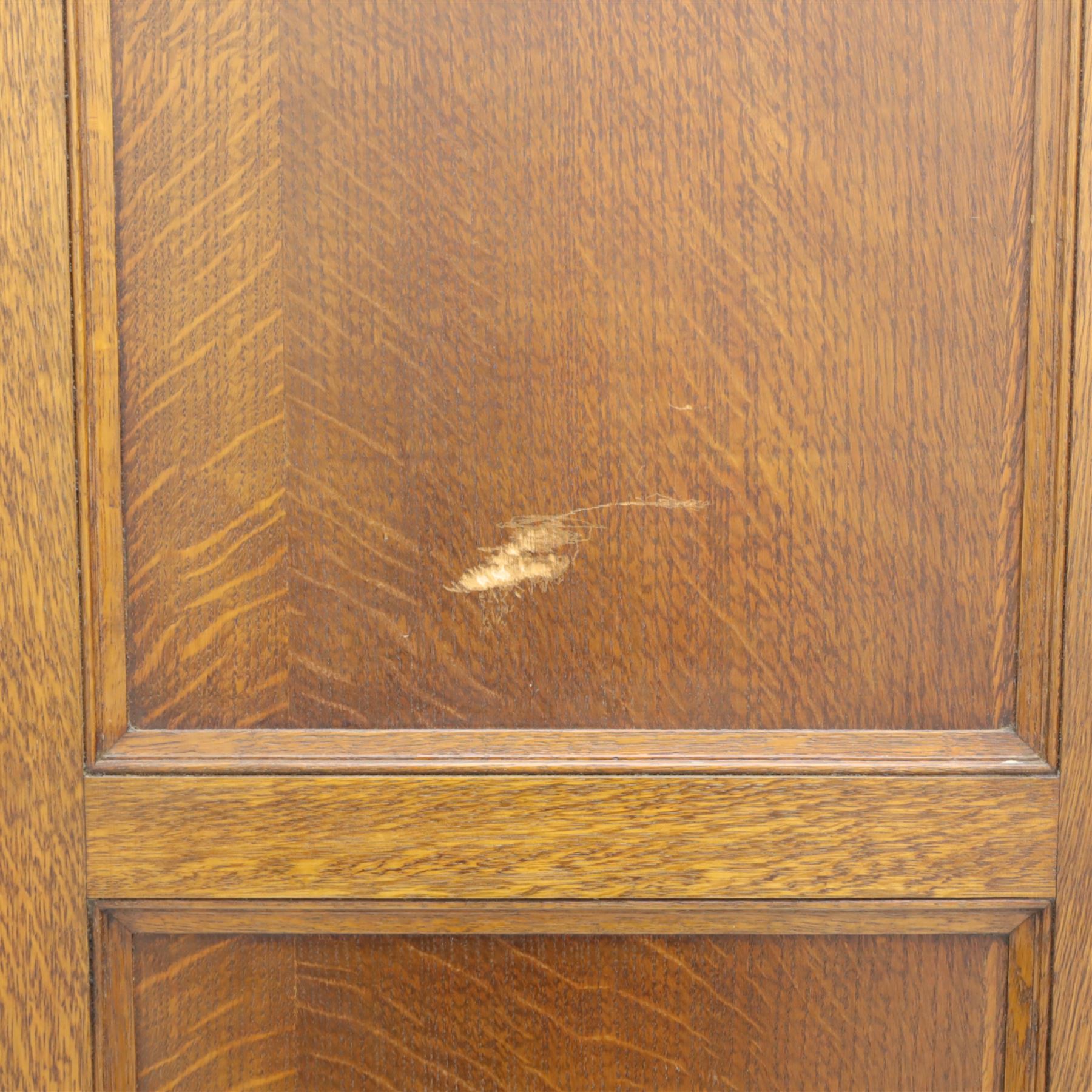 Edwardian oak glazed cabinet, moulded cornice above a panelled front and sides, fitted with lead glazed doors enclosing shelved interior, left side full length cupboard converted to enclose a gun cabinet, on a plain plinth base 
