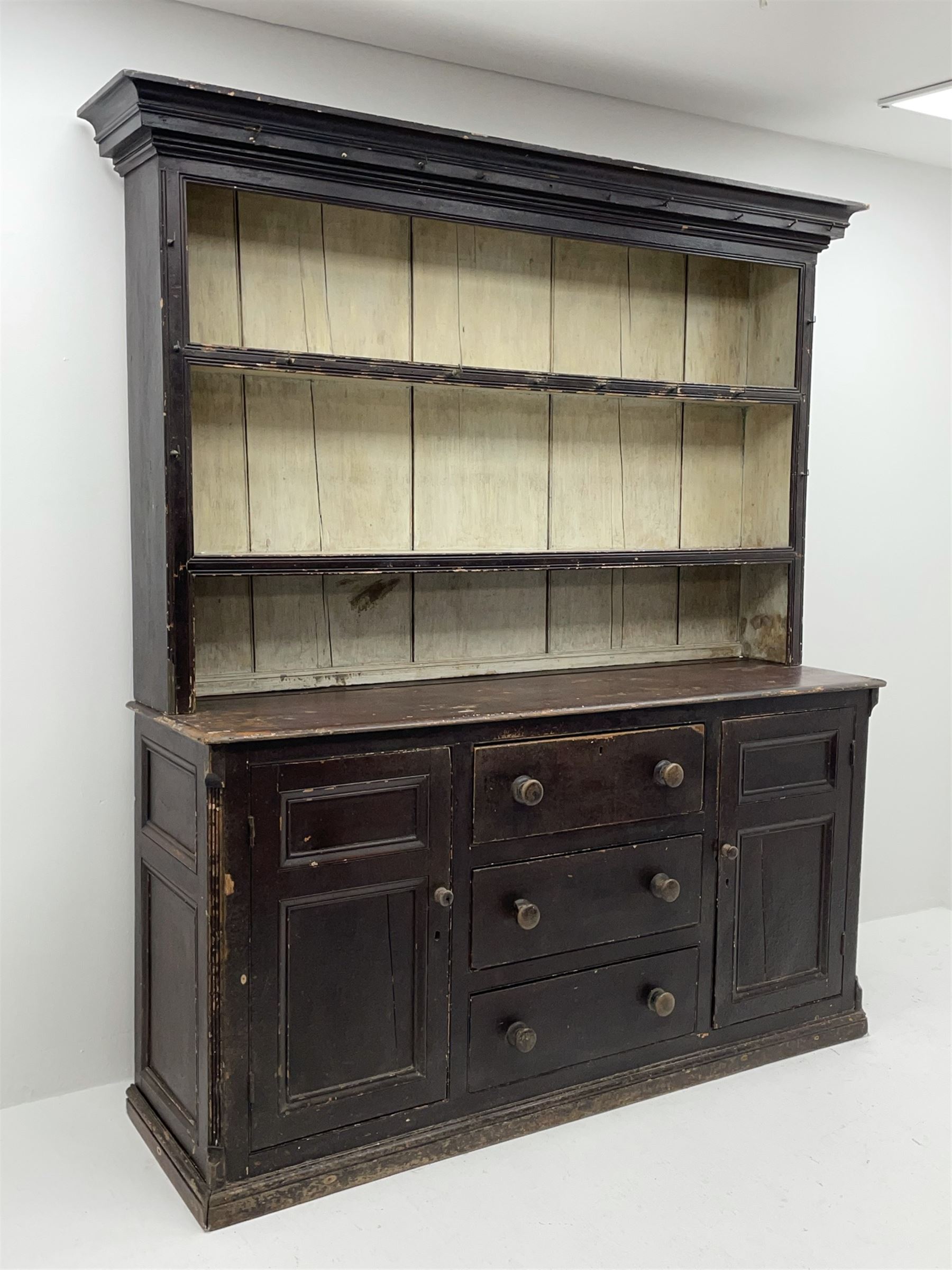 Early 19th century scumbled pine dresser, the projecting cornice over two heights plate rack with moulded frame, the base with reeded canted corners fitted with three drawers and two panelled cupboards, panelled sides, moulded skirt base