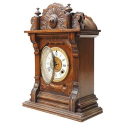 Late 19th century-8-day American Ansonia mantle clock, in a carved oak case with an enamel dial and gilt dial bezel, twin train spring driven movement striking the hours on a coiled gong. With pendulum.