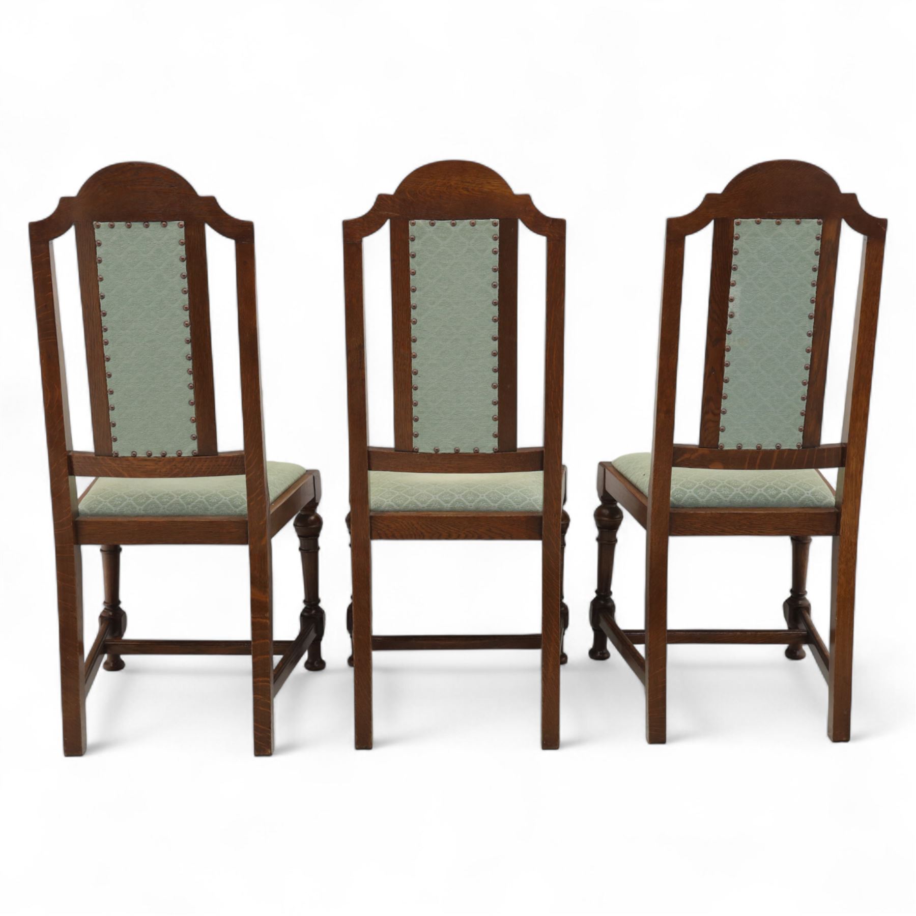 Victorian mahogany extending dining table, rectangular top with chamfered corners above a plain frieze raised on turned reeded legs with castors and two additional leaves, 197cm fully extended, and a set of six early 20th century oak upholstered chairs with drop-in seats, arched panelled back splat and close studded border on turned front legs joined by stretchers, 47x41x109cm 