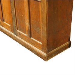 Early 20th century Arts and Crafts oak housekeeper’s cupboard, moulded cornice above pair of panelled doors enclosing a shelved interior, on plinth base