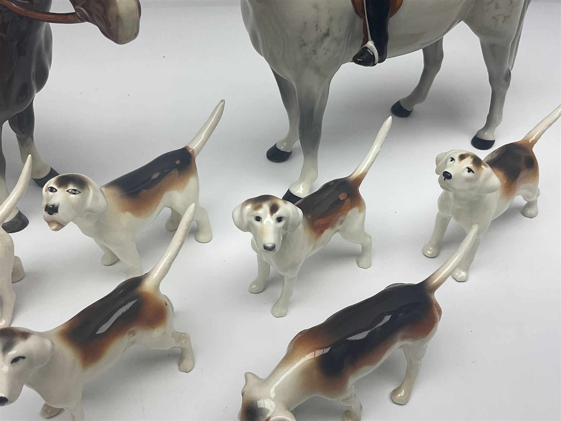 Beswick hunting group, comprising huntswoman on grey horse no 1730, huntsman on brown horse no 1501, fox figure no 1440 and eight fox hounds, all with printed marks beneath (11)