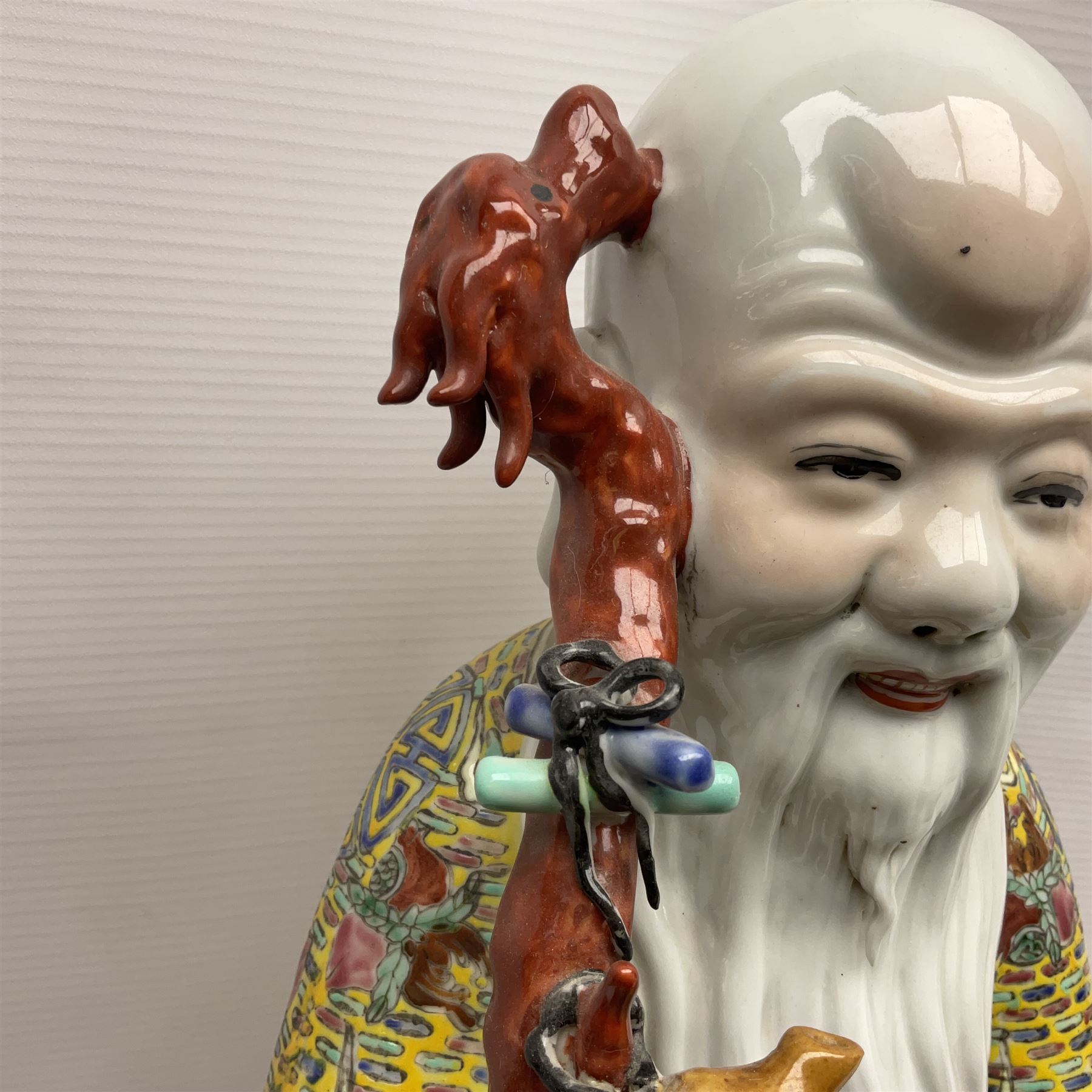 Chinese Republic Period porcelain figure, modelled as Shoulao, wearing elaborately enamelled robes decorated with peaches and flower heads, with impressed mark beneath, H55cm