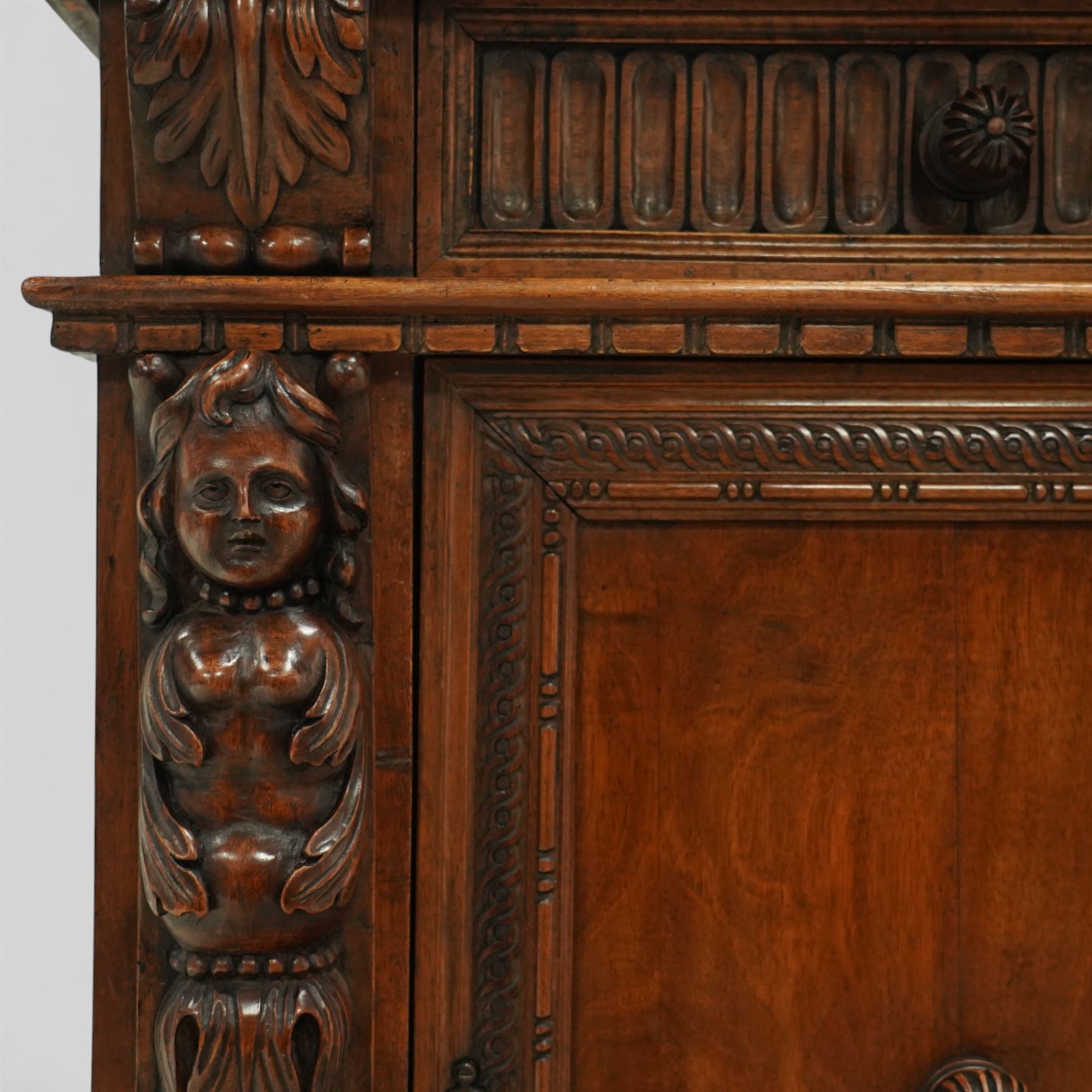 19th century Italian walnut Renaissance Revival side cabinet, the moulded rectangular top above a frieze drawer carved with vertical fluting and a central rosette, with egg-and-dart moulded rails to the top and base, acanthus-carved corbels below, the panelled cupboard door framed by beading and guilloche ornament, flanked by carved caryatids modelled as classical female architectural supports with foliate terminals, raised on paw feet