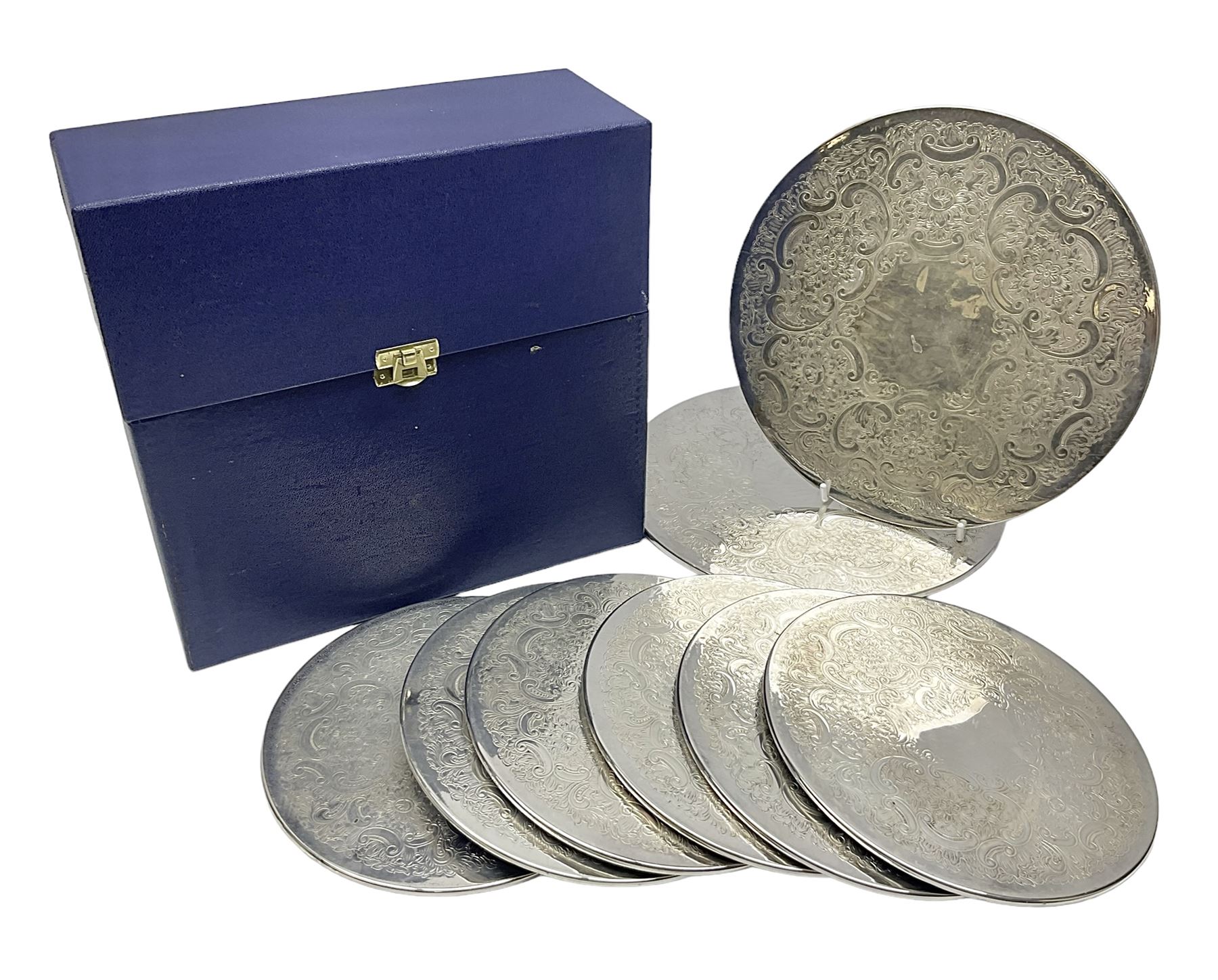 Set of eight silver plated placemats, each of circular form with engraved scroll and floral decoration, including two larger and six smaller examples, largest D23cm, in fitted case 