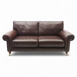Laura Ashley - brown leather two seater sofa, loose cushion back and seat, flanked by scrolled arms upon light stained wood supports on castors