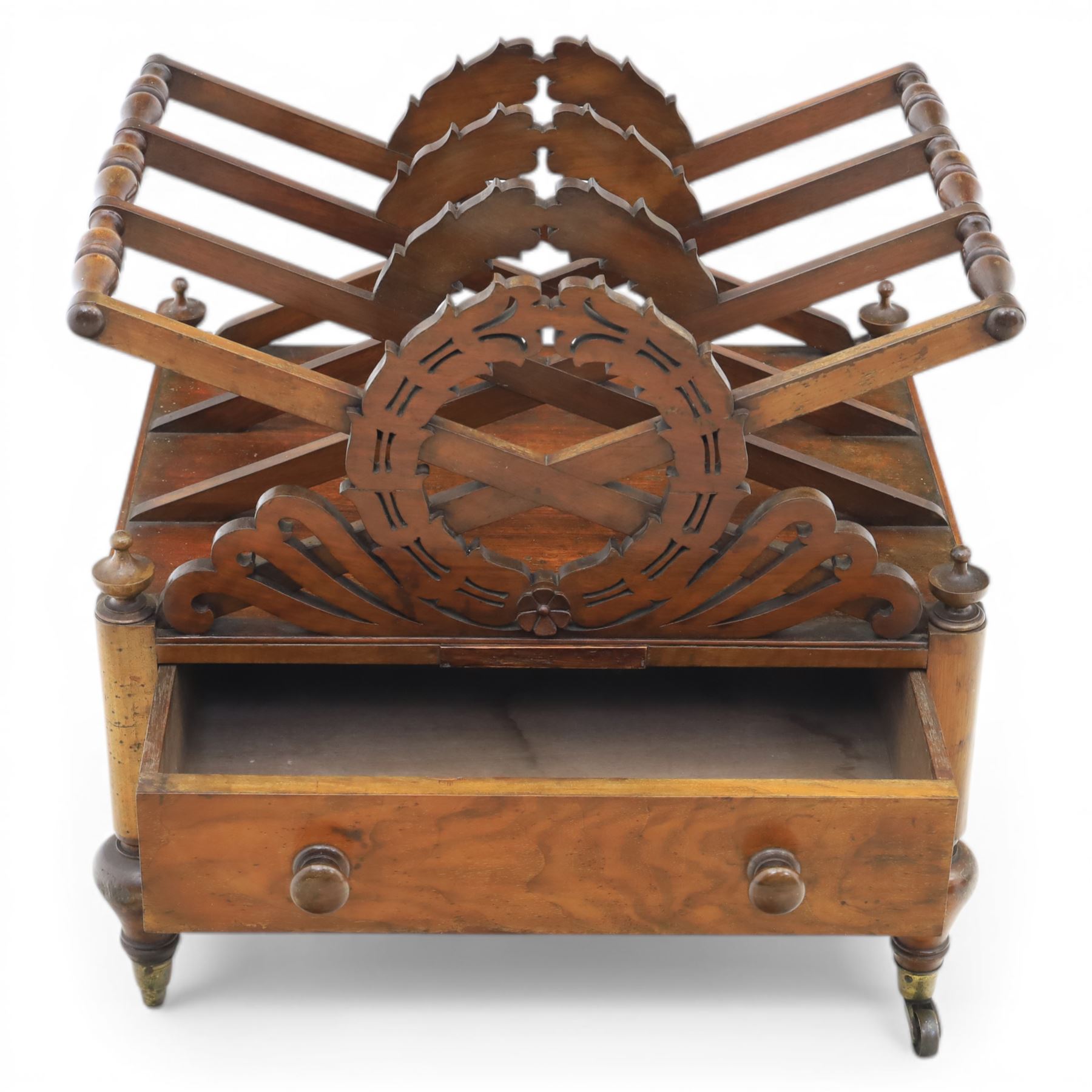 19th century mahogany music canterbury, with pierced dividers united by turned handles, above a single frieze drawer, raised upon baluster supports on brass castors