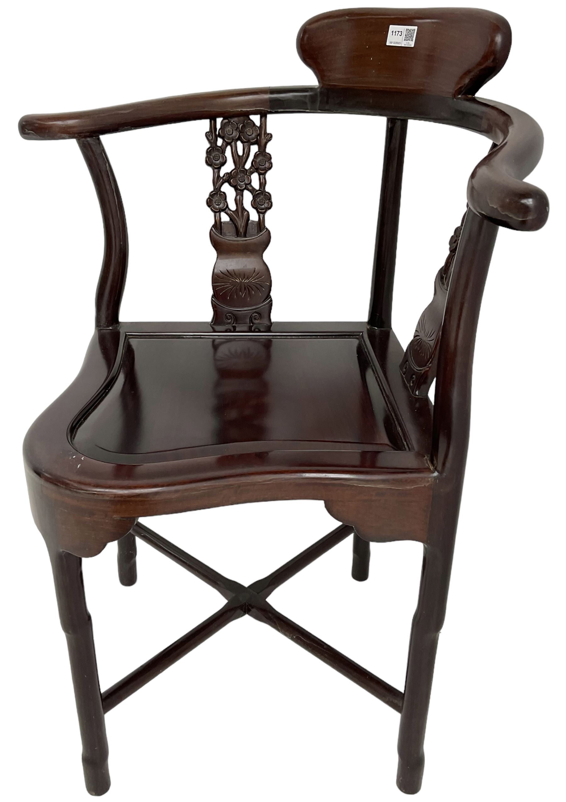 Chinese carved hardwood corner chair, outswept arms over pierced and carved floral splats, raised on shaped cylindrical supports united by X-stretcher